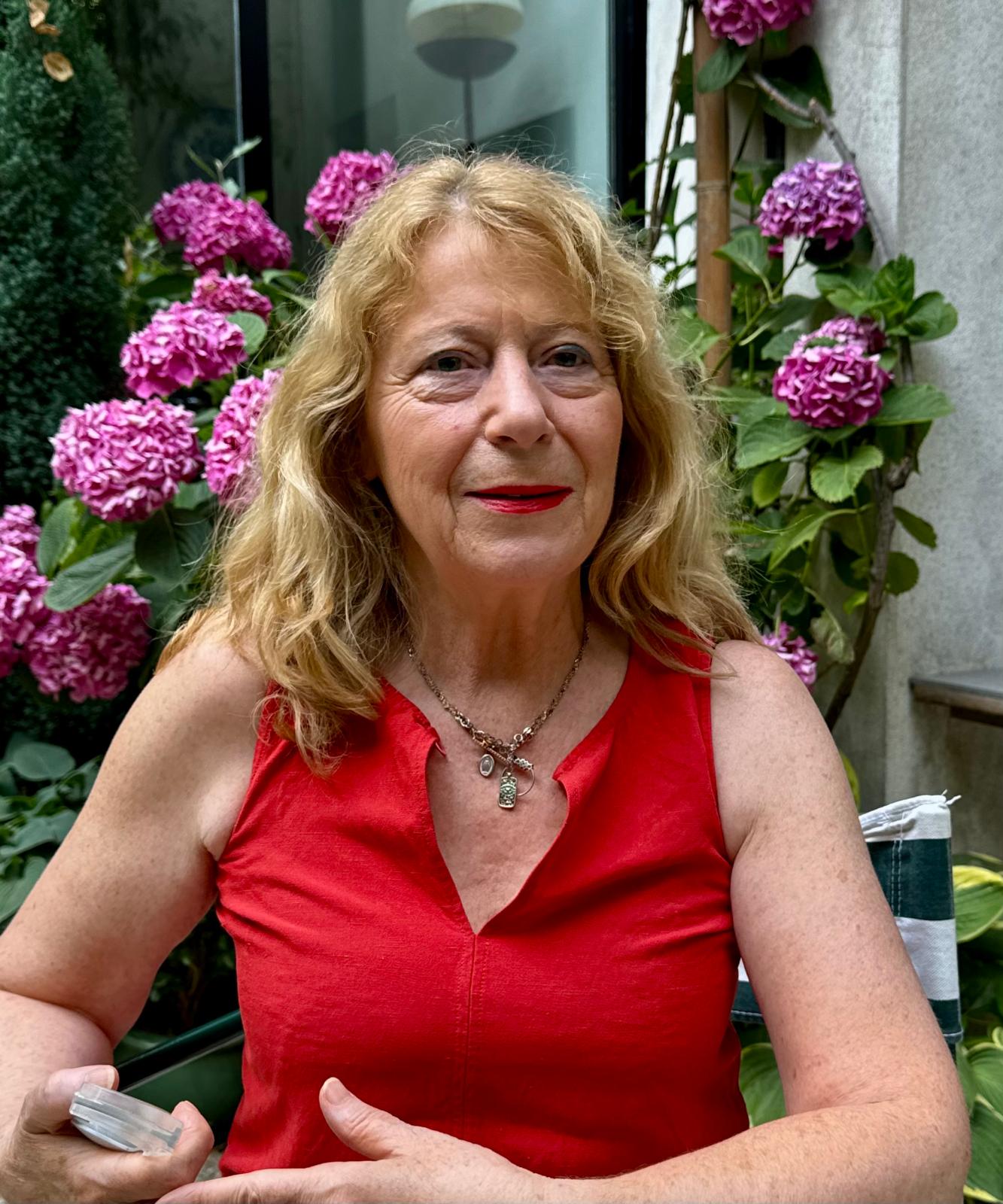 Femme souriante en rouge entourée d'hortensias roses